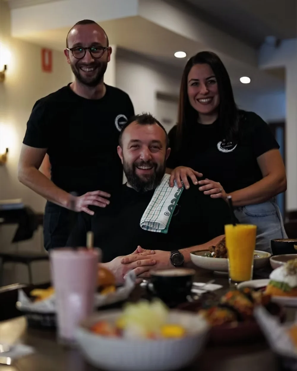 Huso Yilmaz, Mert Toplu and Buket Toplu laughing at a table of Thirty 4 dishes in the café.
